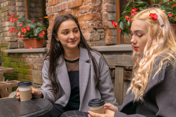 dwie dziewczyny piją kawę na ulicy i rozmawiają - Zdjęcie, obraz