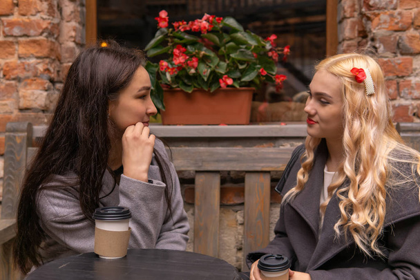 dos chicas están tomando café en la calle y hablando
 - Foto, imagen