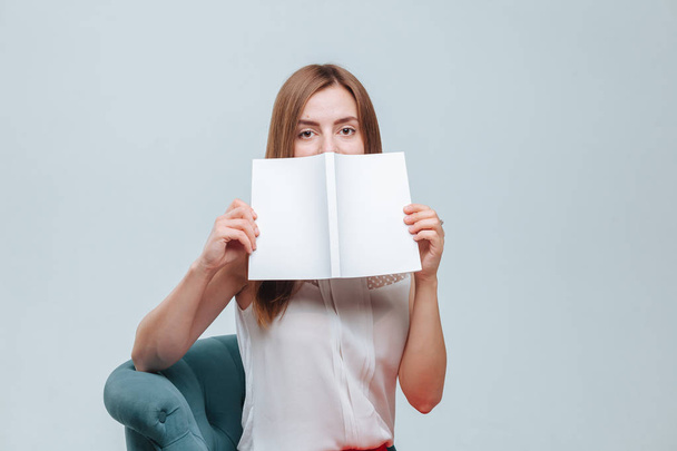 κορίτσι κάλυψε το πρόσωπό της με ένα βιβλίο με λευκό κάλυμμα σε ένα γκρίζο β - Φωτογραφία, εικόνα