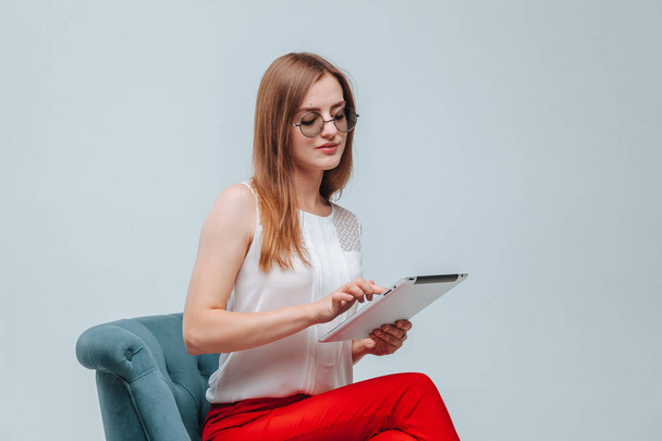 menina trabalha no tablet ela está em calças vermelhas, óculos e sittin
 - Foto, Imagem