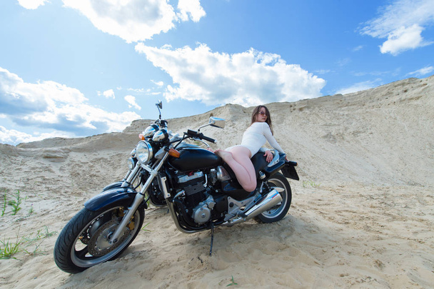 attractive sensual woman lies on motorcycle among the sands  - Foto, imagen