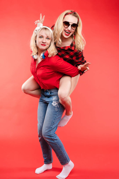 Φιλικό και μοντέρνα κορίτσια αγκαλιάζει πάνω από το κόκκινο φόντο. - Φωτογραφία, εικόνα
