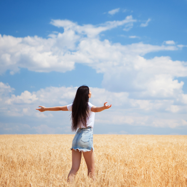 Mujer feliz disfrutando de la vida en el campo Belleza de la naturaleza, cielo azul nublado y campo colorido con trigo dorado. Estilo de vida exterior. Concepto de libertad. Mujer en el campo de verano - Foto, imagen