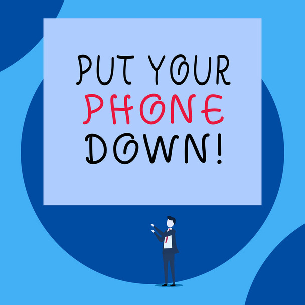 Handwriting text Put Your Phone Down. Concept meaning end telephone connection saying goodbye caller Isolated view young man standing pointing upwards two hands big rectangle. - Photo, Image