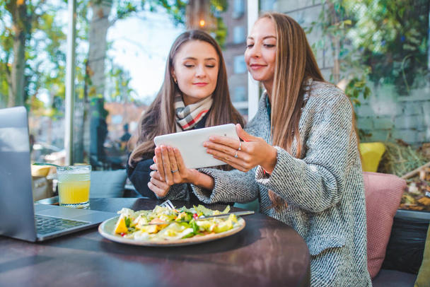 duas mulheres adultas jovens têm reunião no café ao ar livre trabalhando no laptop
 - Foto, Imagem