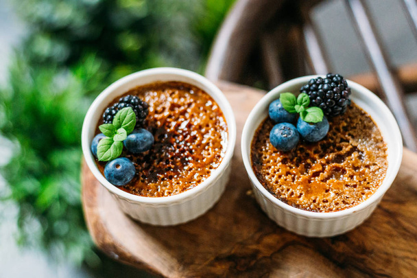 Creme Brulee with Berries on Dark Background with Green Plants A - Foto, Bild