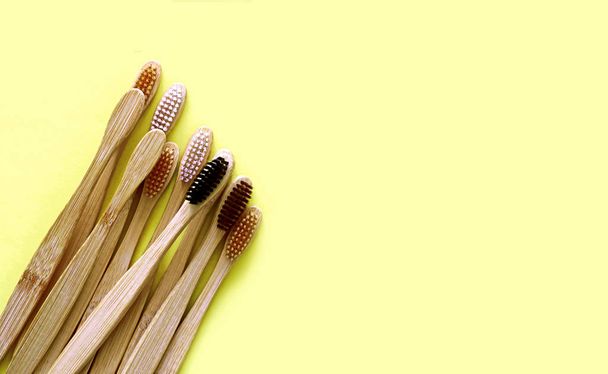 Escovas de dentes de bambu no fundo amarelo da moda. Produtos ecológicos. Eco, zero resíduos e conceitos de saúde. Deitado. Lugar para SMS. Material biodegradável
 - Foto, Imagem