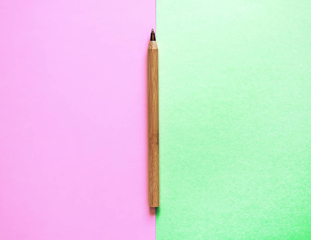 ピンクとグリーン:2つの背景の端に茶色のリサイクルエコペン。平らな横たわる。テキスト用に配置します。エコとチョイスのコンセプト - 写真・画像