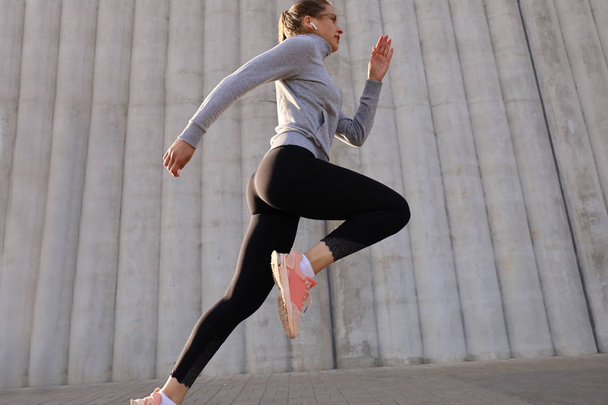 Young attractive woman with perfect slim body running outdoors. Fitness and running concept - 写真・画像