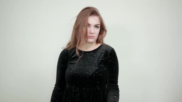chica de cabello castaño en vestido negro sobre fondo blanco aislado muestra emociones
 - Metraje, vídeo