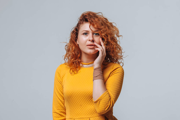A red haired girl in a yellow dress on a light gray background s - Fotoğraf, Görsel