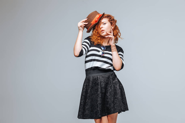 red-haired girl posing in a hat on a gray background - Photo, Image