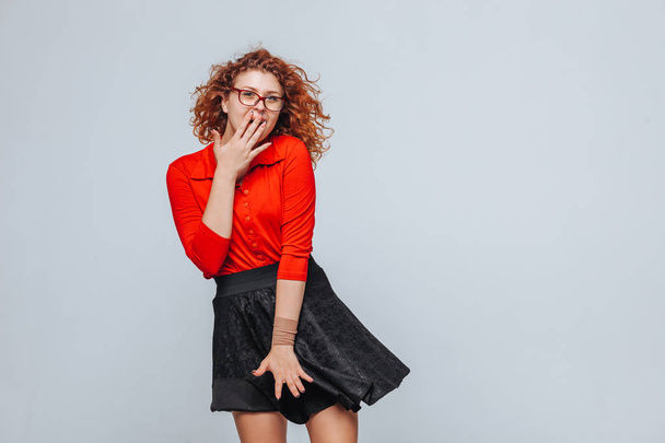 Curly redhead girl in red skirt and glasses surprised - Фото, изображение