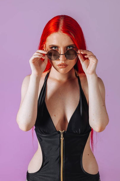 Portrait of a girl with red hair and round glasses on a pink bac - Photo, Image