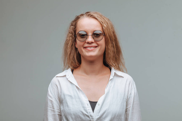Tyttö pyöreä lasit ja valkoinen paita harmaalla taustalla
 - Valokuva, kuva