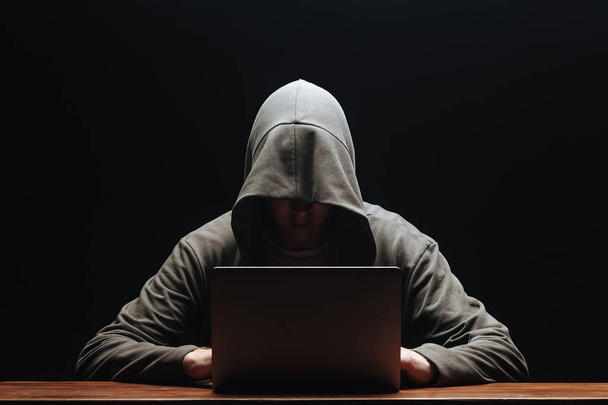 Hacker v digestoři s laptopem na černém pozadí - Fotografie, Obrázek