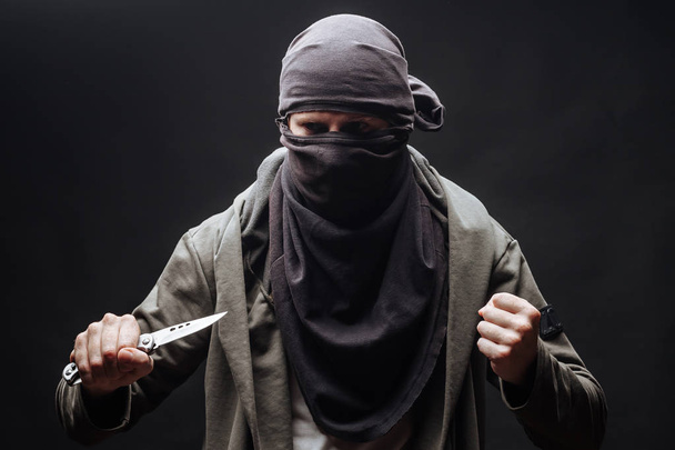  преступник в маске угрожает ножом темным фоном
 - Фото, изображение