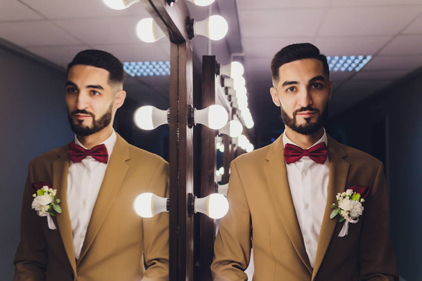 Handsome strong stylish bearded groom posing near mirror. - Fotó, kép