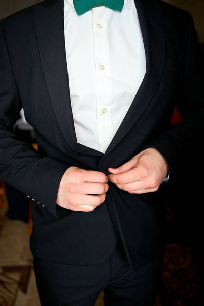 Apuesto novio vistiéndose y preparándose para la boda. Elegante joven hombre de moda vestirse para la celebración de la boda
. - Foto, Imagen