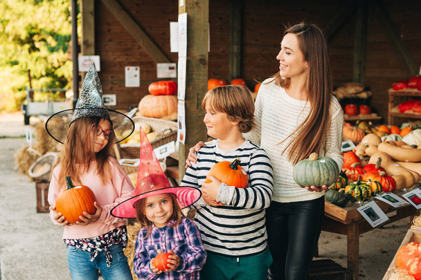 Family with kids choosing halloween pumpkin on farm market - Foto, afbeelding