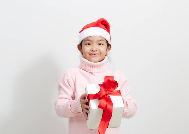 Dziewczyna trzyma pudełko na prezent w swetrze i kapeluszu Świętego Mikołaja - Zdjęcie, obraz