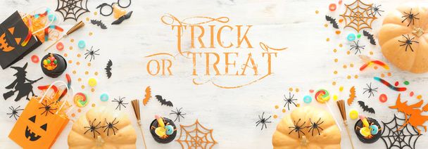 holidays image of Halloween. Pumpkins, bats, treats and cute witch over white wooden background. top view, flat lay. banner - Foto, Bild