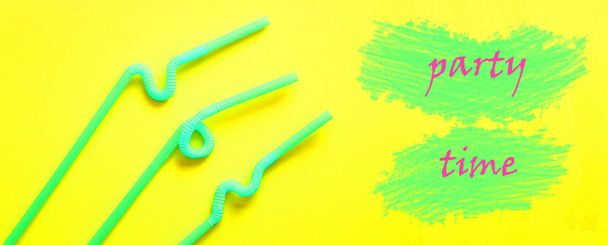 Tubes à cocktail en plastique vert avec une partie flexible, grâce à laquelle ils peuvent être tordus en un noeud ou en zigzag, sur un fond jaune. Les mots "TEMPS DE PARTIE" sont écrits sur des taches vertes dessinées comme une peinture. Concept vacances d'été. Bannière
 - Photo, image