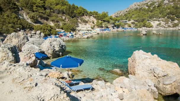 Anthony Quinn Bay Beach Umbrella and Chair in Rhodes Greece with People Swimming in the Clear Mediterranean Sea Water at the Popular Greek Island Destination - Imágenes, Vídeo