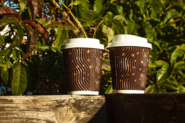 Δύο κυματοειδείς κούπες καφέ σε ένα ξύλινο μπαλκόνι. Ζεστά ποτά για να πάει. - Φωτογραφία, εικόνα