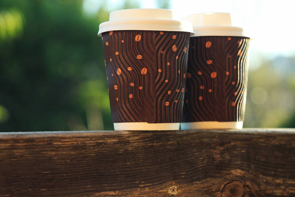 Δύο κυματοειδείς κούπες καφέ σε ένα ξύλινο μπαλκόνι. Ζεστά ποτά για να πάει. - Φωτογραφία, εικόνα