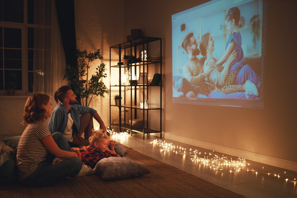 family mother father and children watching projector, TV, movies - Foto, imagen