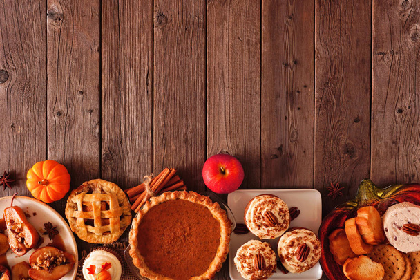 Autumn food bottom border. Table scene with a selection of pies, appetizers and desserts. Top view over a rustic wood background. Copy space. - Foto, Imagem