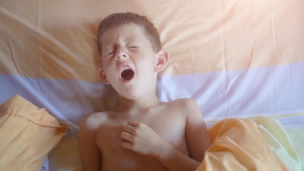 Top view of a young boy yawning in bed - Video
