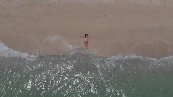 la ragazza giace sulla spiaggia e un'onda rotola su di lei
 - Filmati, video