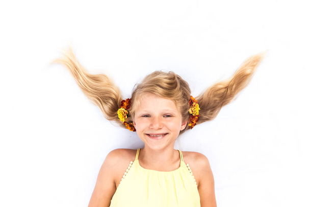bela criança sorridente com penteado engraçado adornado com flores
 - Foto, Imagem