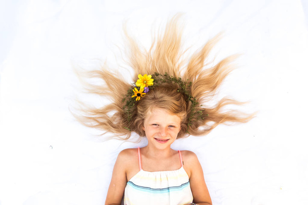 criança bonito com cabelo loiro longo estilizado com decoração floral, tiro da perspectiva dos pássaros - Foto, Imagem