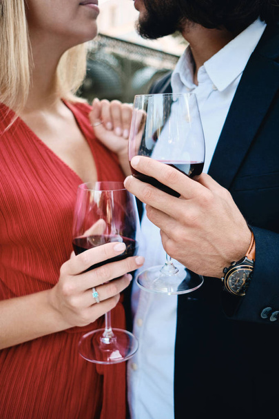 Close up sensual couple with glasses of red wine celebrating engagement in restaurant outdoor - Photo, Image