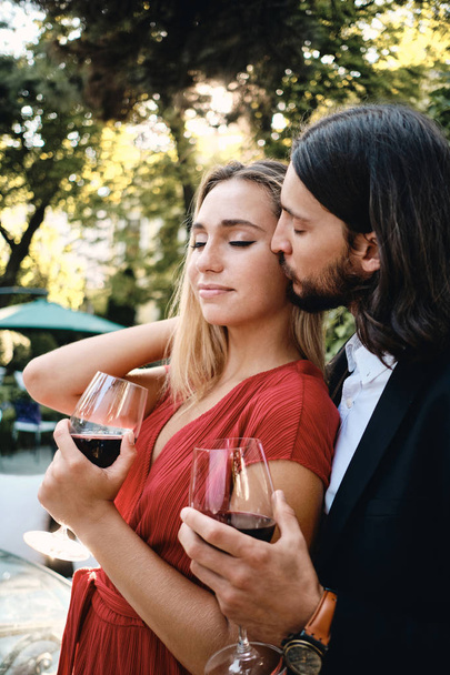 Joven pareja romántica sensual con copas de vino tinto en la fecha en el restaurante al aire libre
 - Foto, Imagen