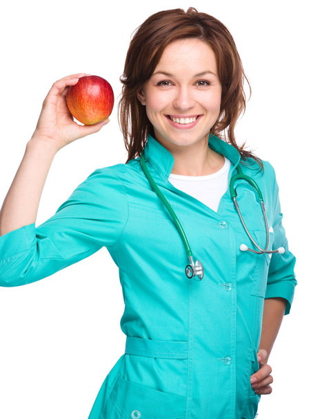 Young lady doctor is holding a red apple - Photo, Image