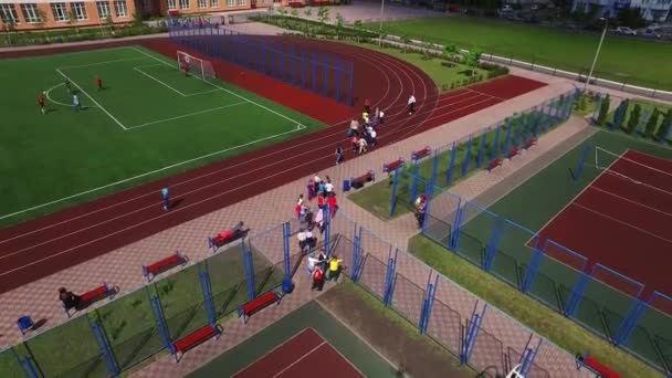 Teenagers playing on soccer field in school yard. Aerial view of sport ground - Materiał filmowy, wideo