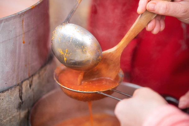A fazer molho de tomate no fogão. Um close-up do moinho de mão grelhando os tomates frescos para fazer molho de tomate
. - Foto, Imagem