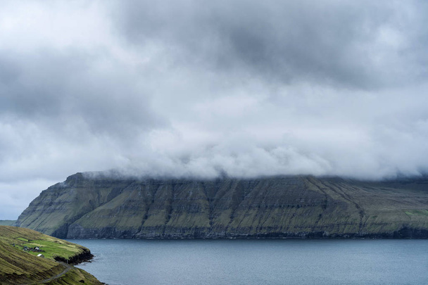 Dramatic landscape of Faroe Islands with grass meadows and rocky cliffs in stormy weather. - Fotoğraf, Görsel