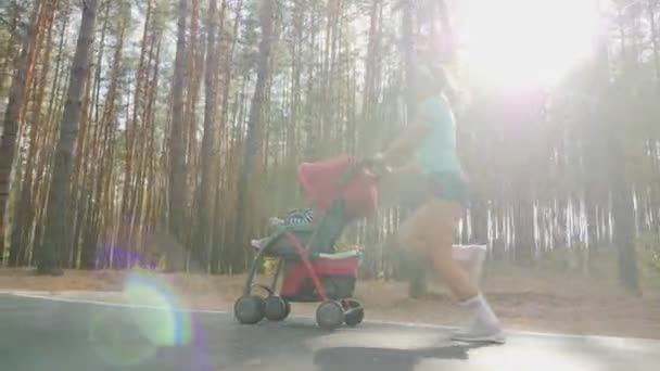 Correndo mulher com carrinho de bebê na estrada na floresta
 - Filmagem, Vídeo