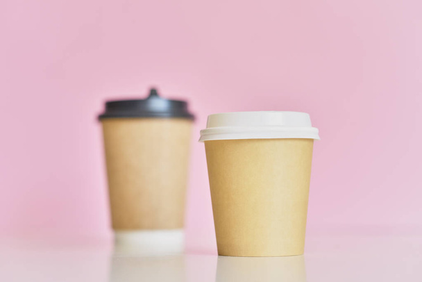 zwei Kaffeetassen aus Papier auf rosa Hintergrund. Kreatives Mockup-Image - Foto, Bild