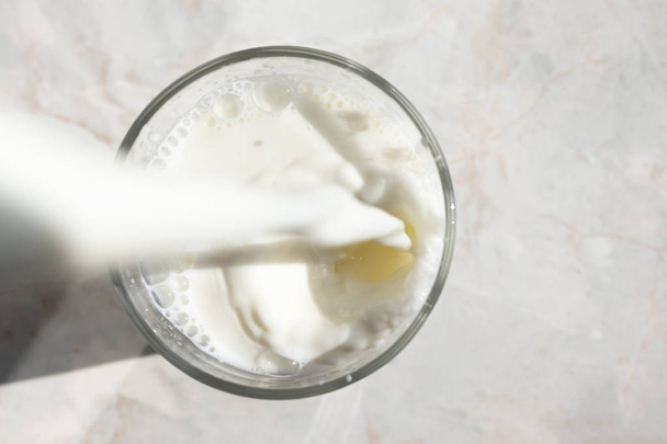 Primo piano del flusso di latte fresco versando in un bicchiere con spruzzata a
 - Foto, immagini