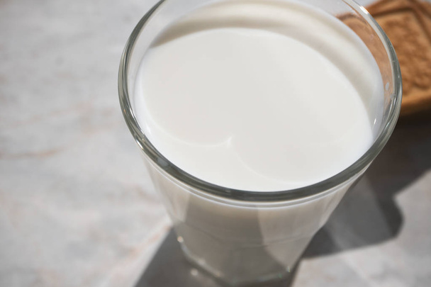 Крупный план поверхности молока в стекле и булочки на заднем плане
 - Фото, изображение