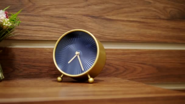 stylish alarm clock and a small bouquet of artificial flowers on the bedside table - Footage, Video