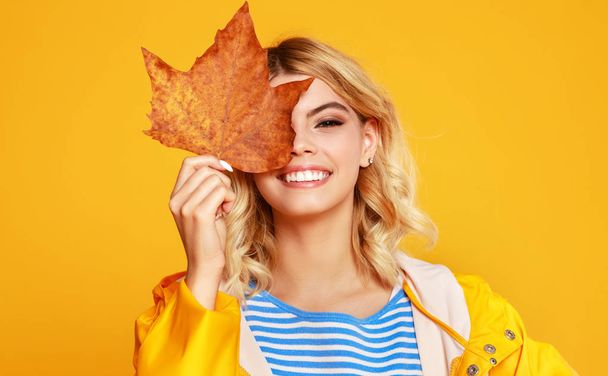 happy emotional girl with autumn leaves on colored yellow backgr - Photo, Image