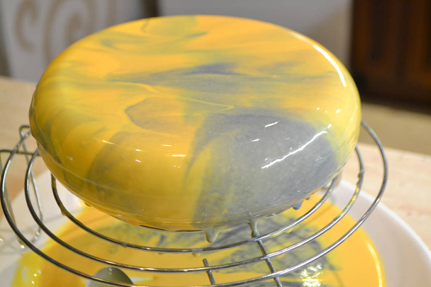 Um bolo de mousse com esmalte espelho em amarelo e violeta ou azul
. - Foto, Imagem