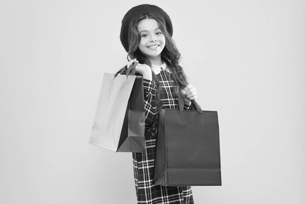 big sales. happy girl with long curly hair in beret. shopping. child with shopping bag. parisian child on yellow. little beauty shopaholic. Holiday present. little girl in hat. shopping sales - Valokuva, kuva